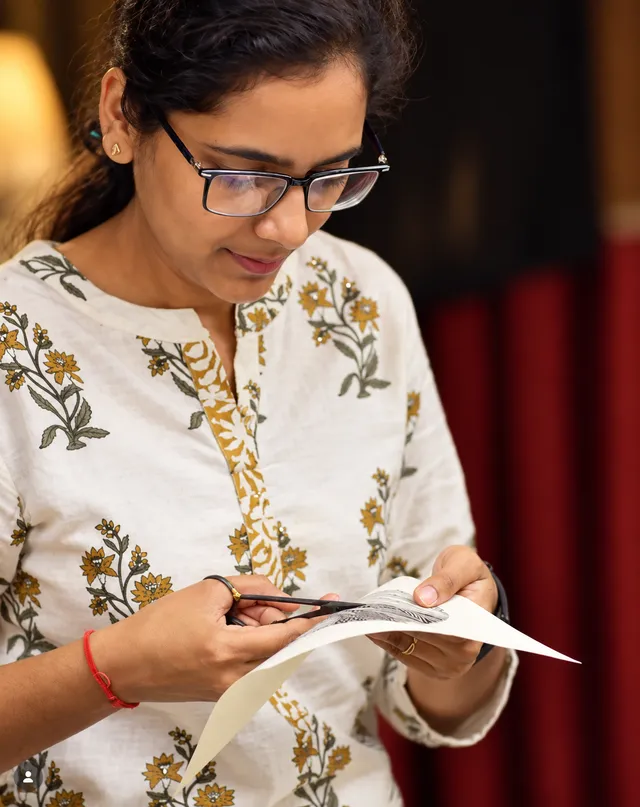 Sakshi Garg cuts a fine Sanjhi design from paper.