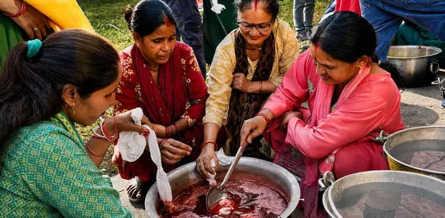 Women artisans in the Garhwal Himalayas stir plant material in a dye vat.